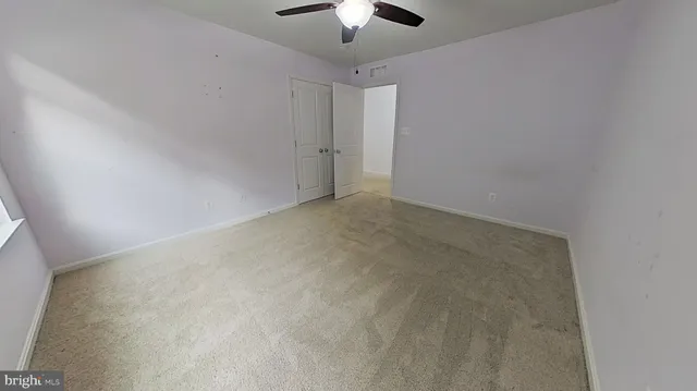 an empty room with a chandelier fan and windows