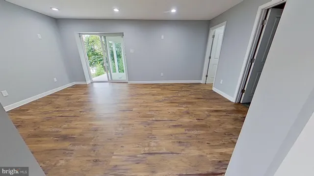 a view of wooden floor in an empty room with a window