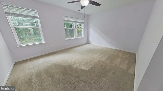 an empty room with a window and a chandelier fan
