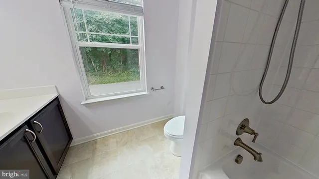 a bathroom with a granite countertop sink and a toilet