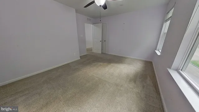 an empty room with a ceiling fan and carpet