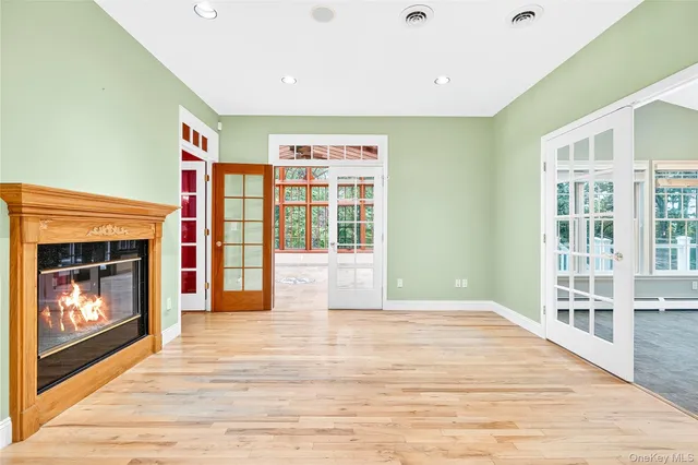 a view of an empty room with wooden floor fireplace and a window
