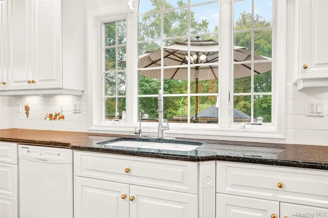 a kitchen with granite countertop white cabinets and a window