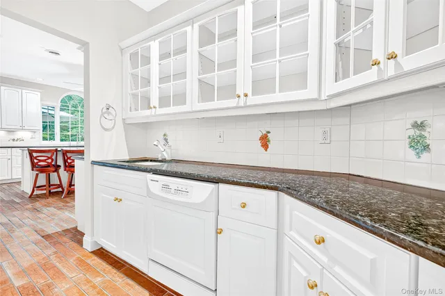 a kitchen with granite countertop stainless steel appliances white cabinets and a window