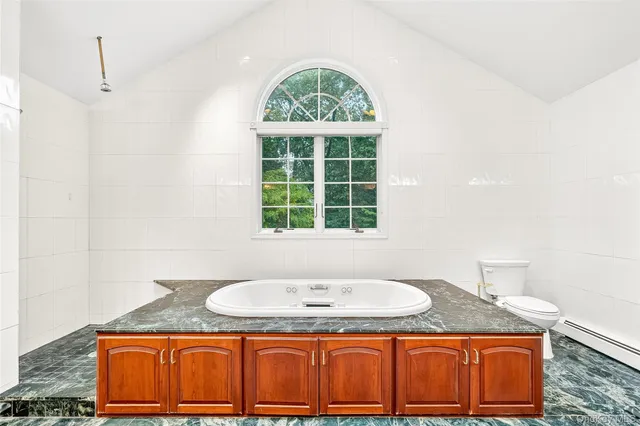 a bathroom with a granite countertop tub sink and mirror