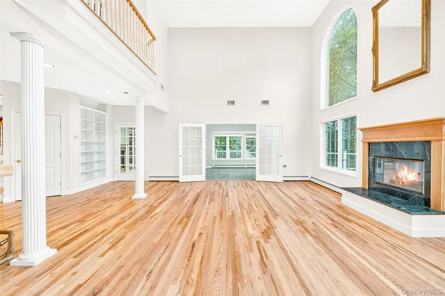 a view of an empty room with wooden floor fireplace and a window