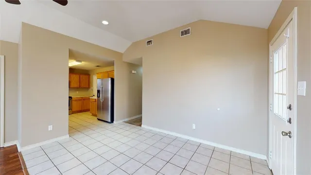 a view of a hallway with wooden floor and a refrigerator in a room