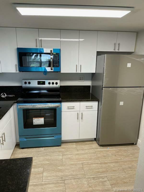 Welleby Sunrise, FL 33351 - Photo 7 of 9 a kitchen with granite countertop a stove and a refrigerator