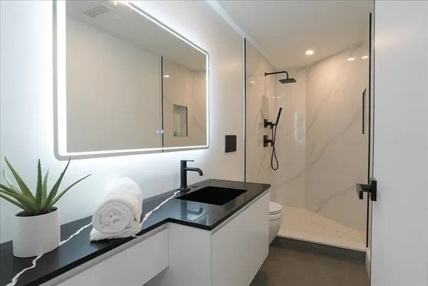 a bathroom with a granite countertop sink a mirror and a shower