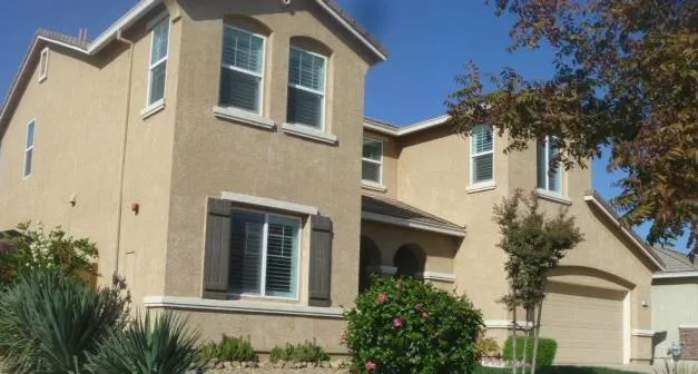 a view of a white house with a large windows and flower plants