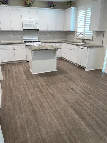 a kitchen with granite countertop wooden cabinets and white appliances