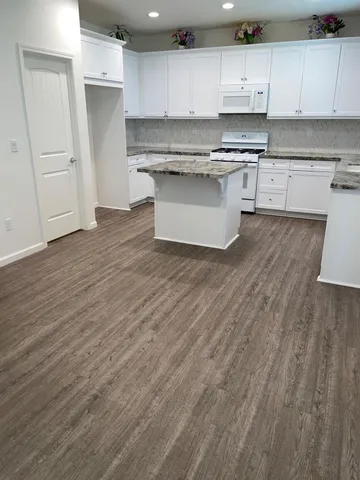 a kitchen with granite countertop a sink cabinets and wooden floor