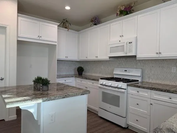 a kitchen with granite countertop white cabinets and white appliances