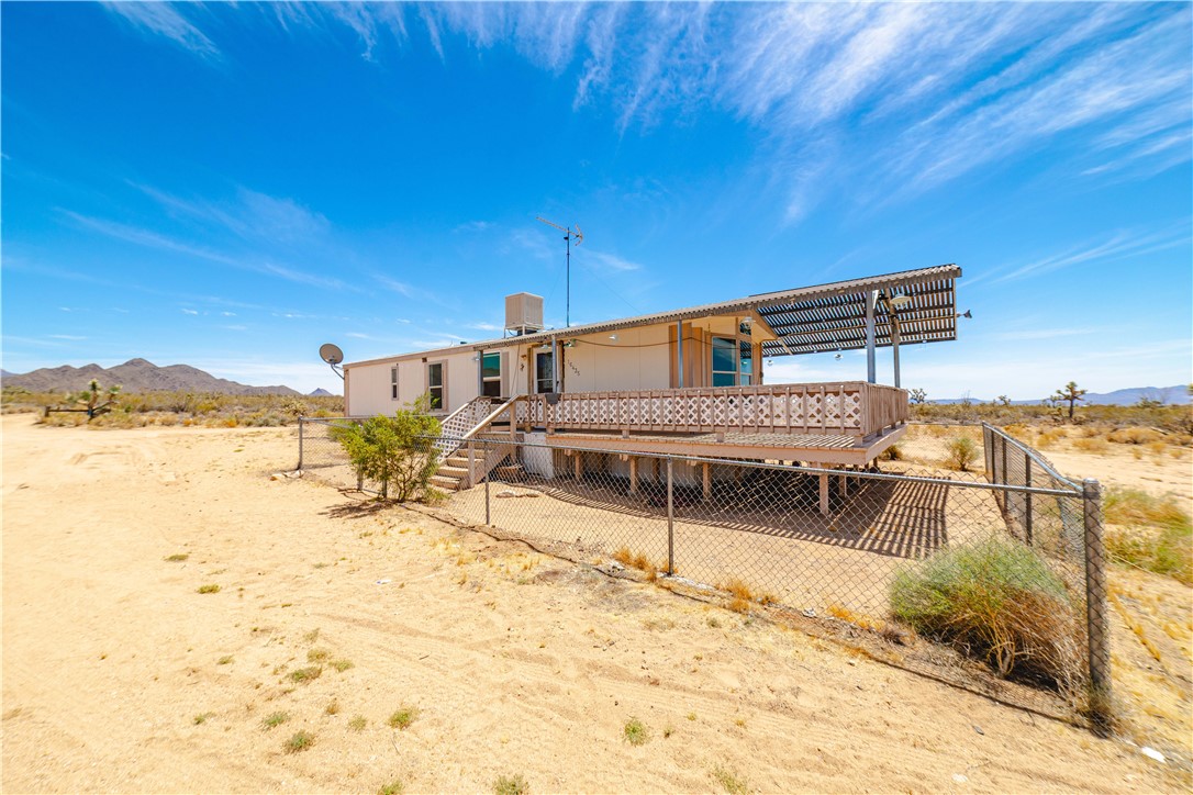 16435 South Wyatt Earp Road Yucca, AZ 86438 - Photo 55 of 57 Elevated mobile home featuring a large outdoor deck with decorative railing, an extended sunshade, and direct stair access
