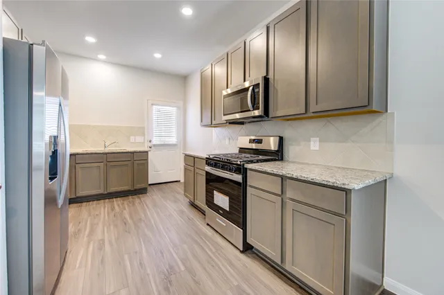 a kitchen with stainless steel appliances granite countertop a stove a sink and a refrigerator