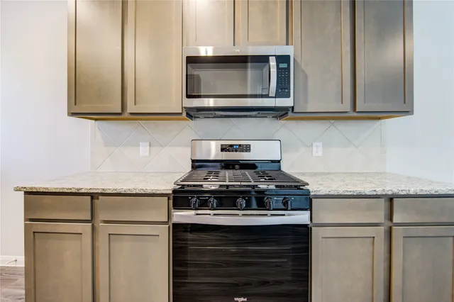 a kitchen with stainless steel appliances granite countertop white cabinets stove top oven and microwave