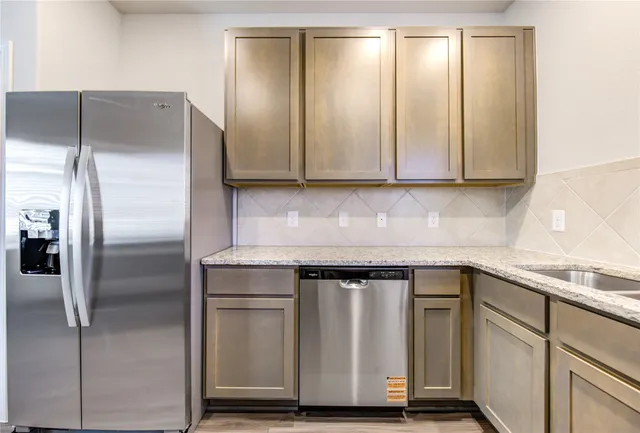 a kitchen with granite countertop a refrigerator and cabinets