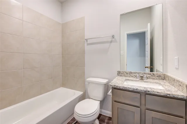 a bathroom with a granite countertop toilet a sink and a bathtub