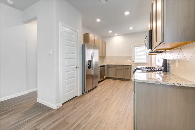 a kitchen with stainless steel appliances granite countertop a refrigerator a sink and wooden cabinets