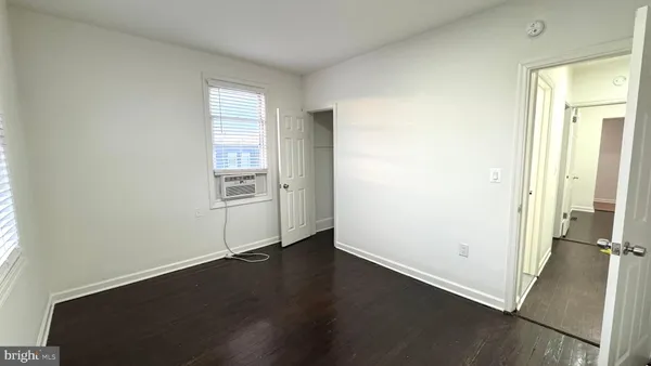 an empty room with wooden floor cabinet and windows
