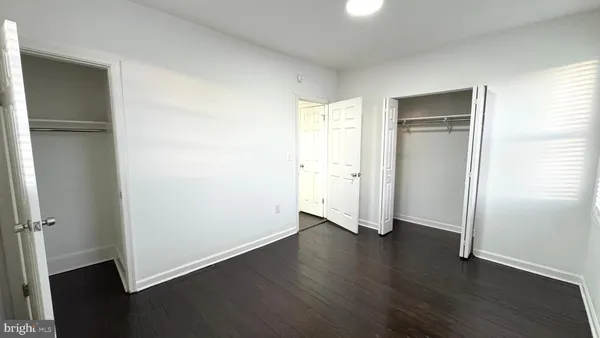 an empty room with wooden floor closet and windows