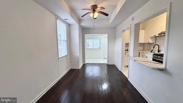 a view of a hallway with wooden floor and a living room