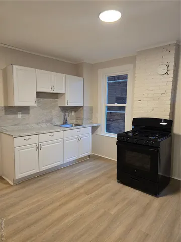 a kitchen with granite countertop a stove a sink and a refrigerator