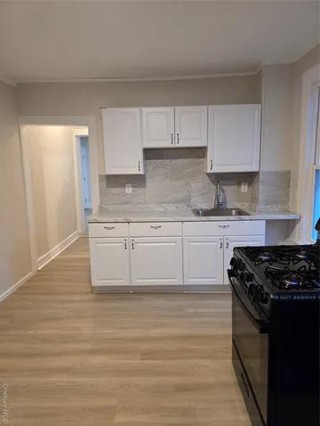 a kitchen with stainless steel appliances granite countertop a stove a sink and white cabinets