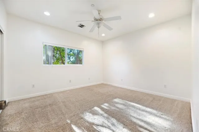 an empty room with windows and ceiling fan