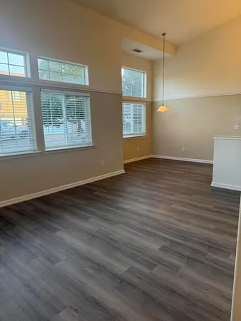 an empty room with wooden floor and windows