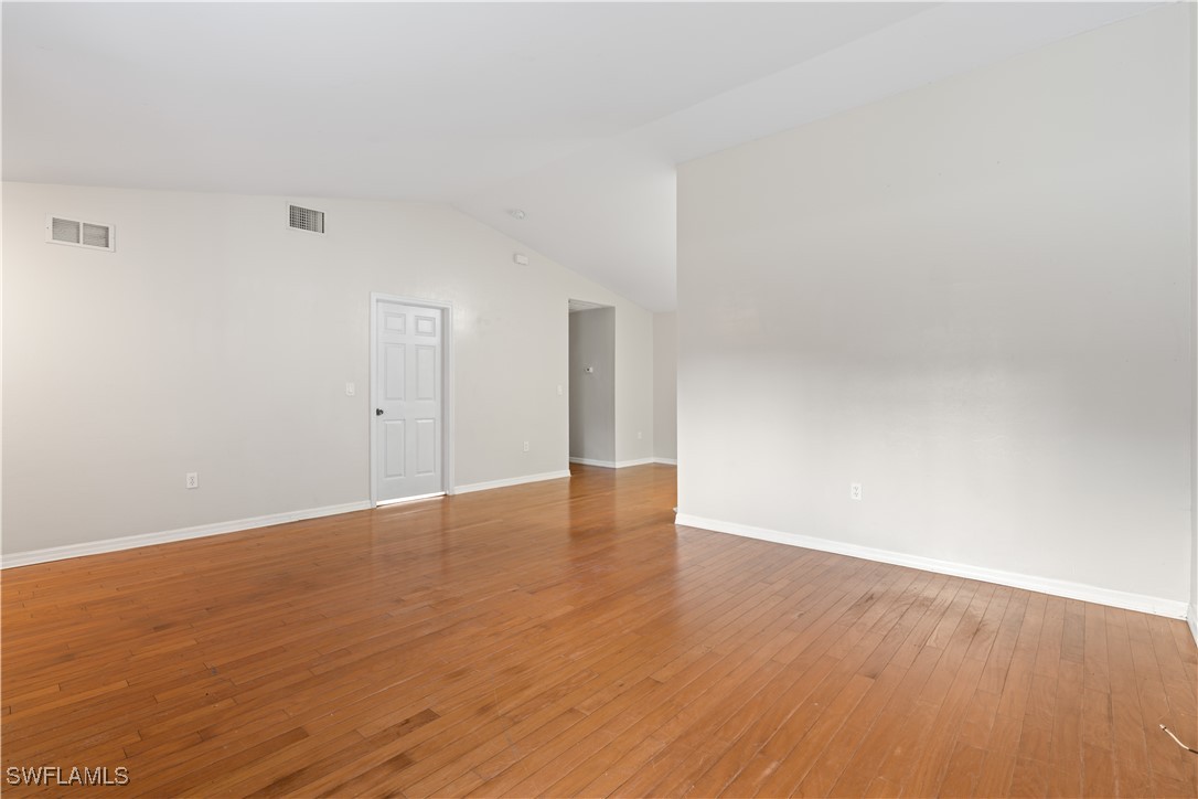209 Meadow Road Lehigh Acres, FL 33973 - Photo 15 of 48 a view of an empty room with wooden floor