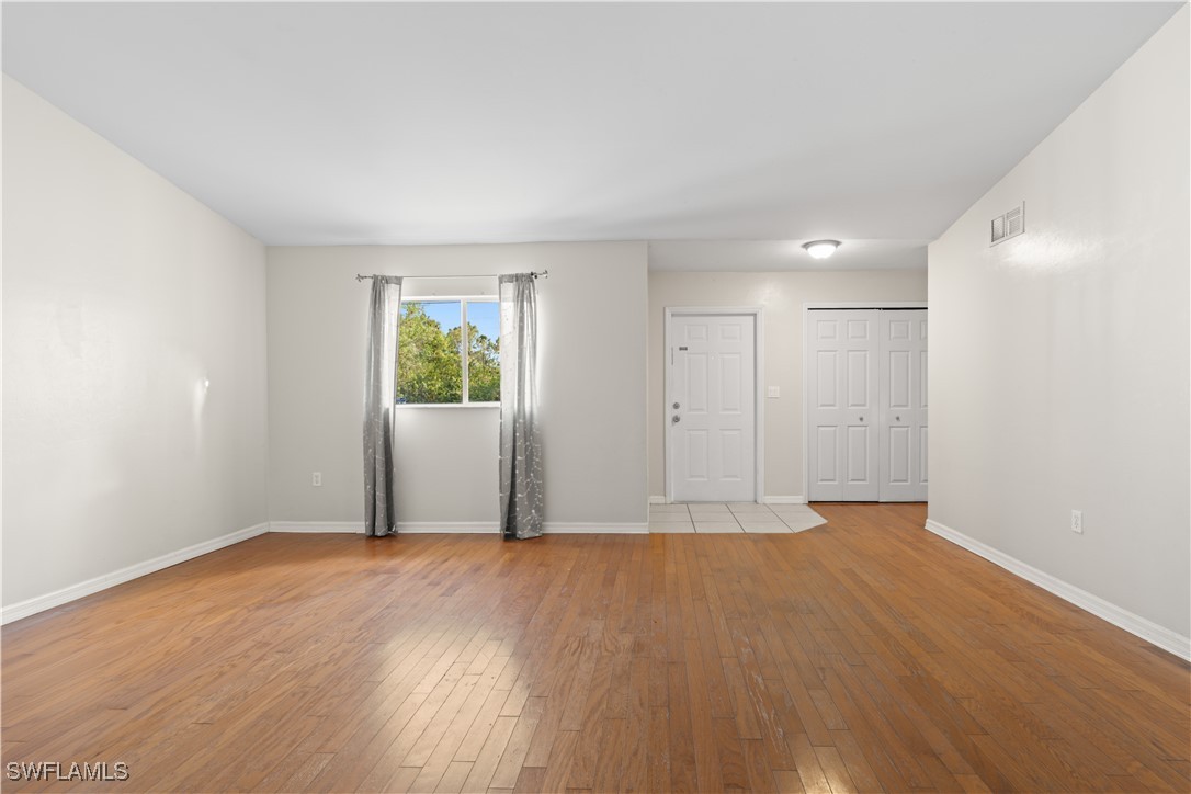 209 Meadow Road Lehigh Acres, FL 33973 - Photo 17 of 48 an empty room with wooden floor and windows