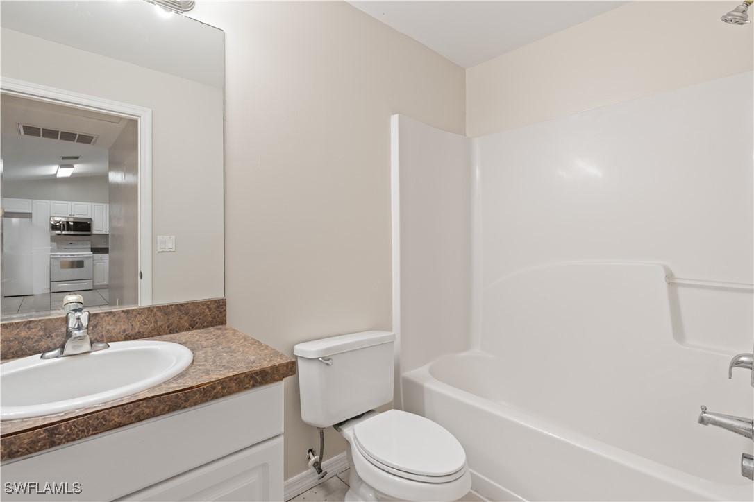 209 Meadow Road Lehigh Acres, FL 33973 - Photo 22 of 48 a bathroom with a granite countertop toilet a sink and a bathtub