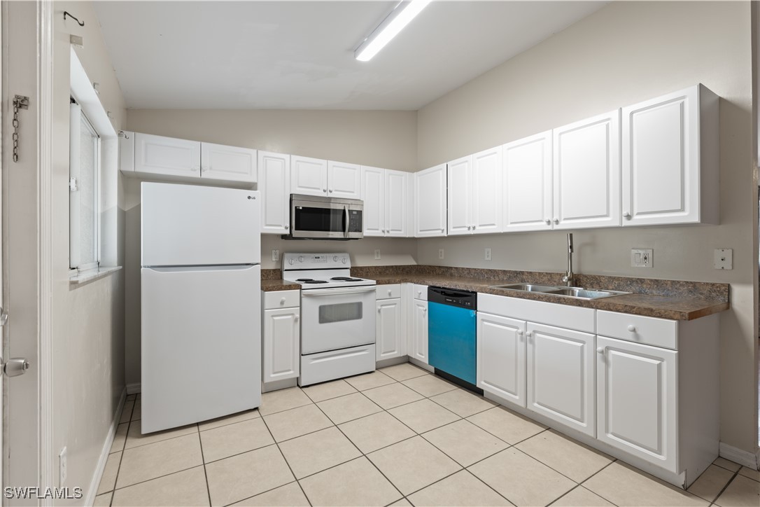 209 Meadow Road Lehigh Acres, FL 33973 - Photo 4 of 48 a kitchen with white cabinets stainless steel appliances and a sink