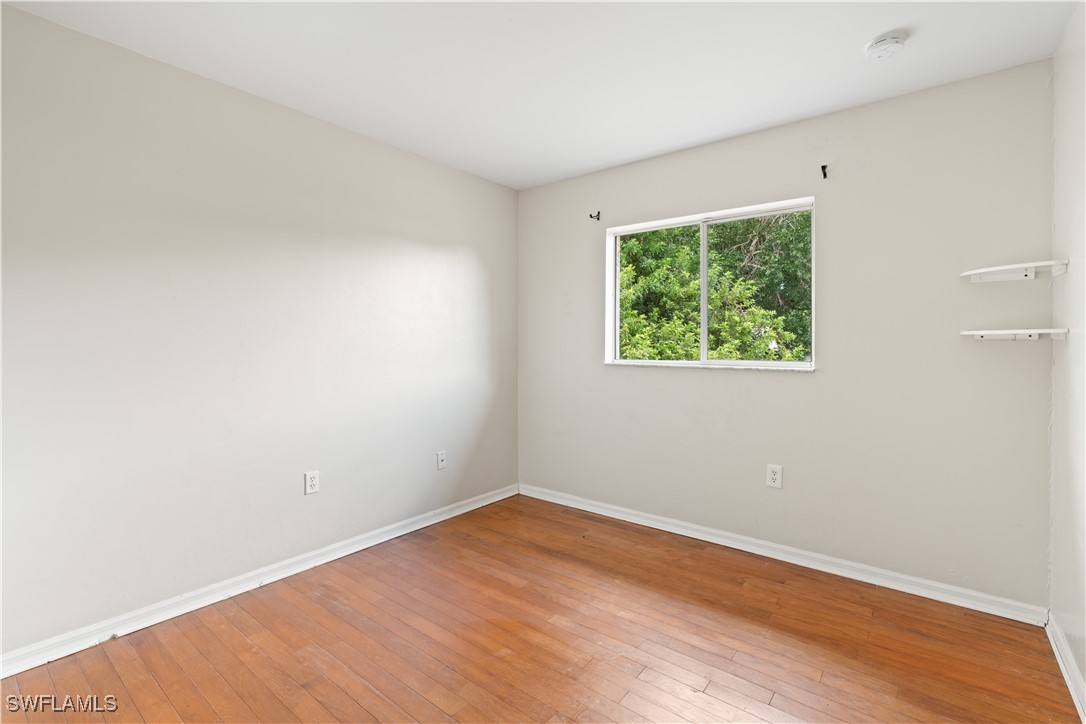 209 Meadow Road Lehigh Acres, FL 33973 - Photo 6 of 48 an empty room with wooden floor and windows