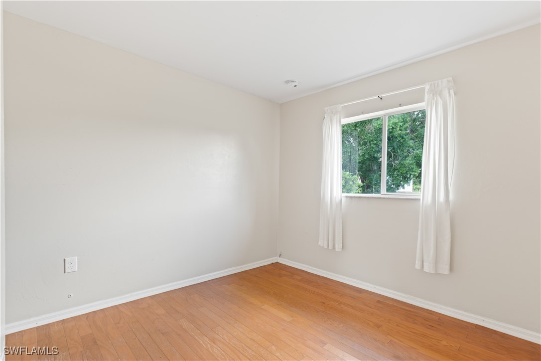 209 Meadow Road Lehigh Acres, FL 33973 - Photo 9 of 48 an empty room with wooden floor and windows