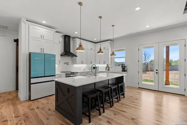 a kitchen with stainless steel appliances granite countertop a refrigerator a sink dishwasher a stove and a dining table with wooden floor