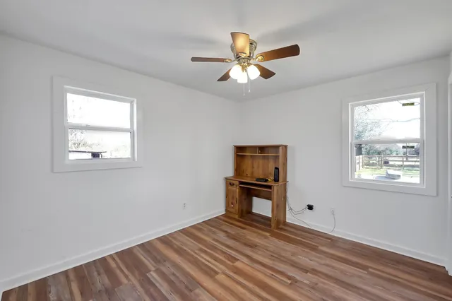 a view of an empty room with wooden floor and a window