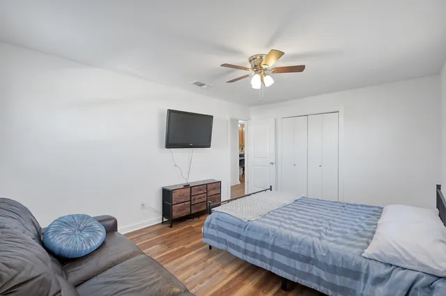 a bedroom with a bed and a dresser with wooden floor