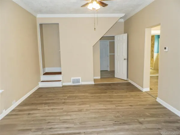 a view of an empty room with window and wooden floor