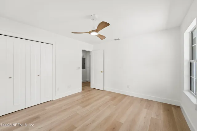 a view of empty room with wooden floor and fan