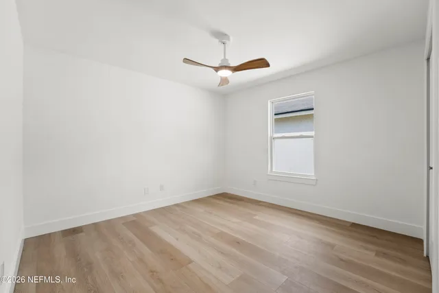 an empty room with a window and a ceiling fan