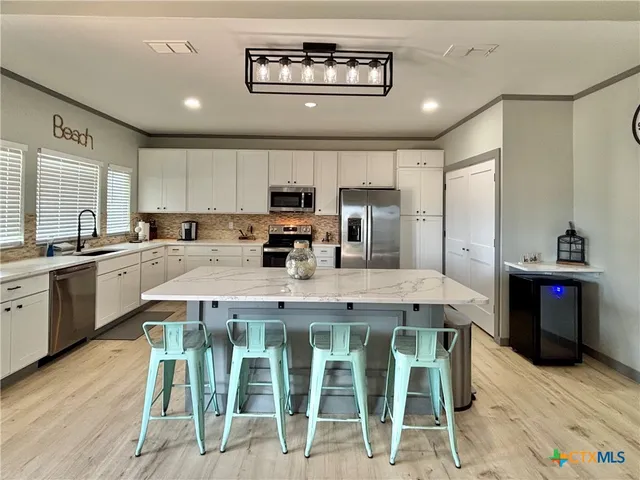 a kitchen with stainless steel appliances kitchen island granite countertop a table chairs sink and cabinets