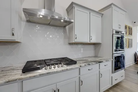 a kitchen with granite countertop a stove and a white cabinets