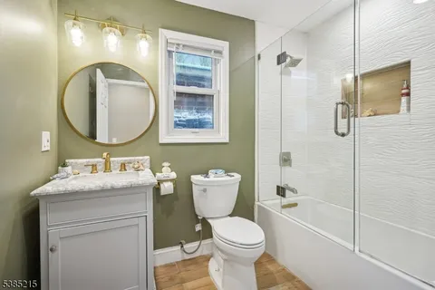 a bathroom with a toilet sink vanity granite and shower
