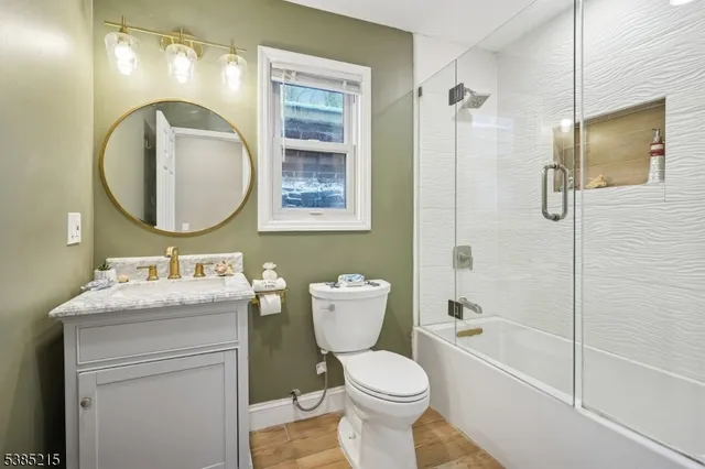 a bathroom with a toilet sink vanity granite and shower