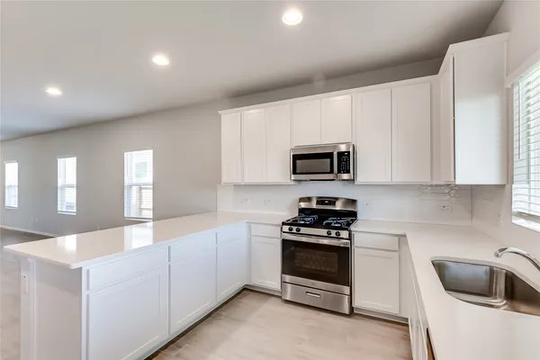 a kitchen with granite countertop white cabinets and stainless steel appliances