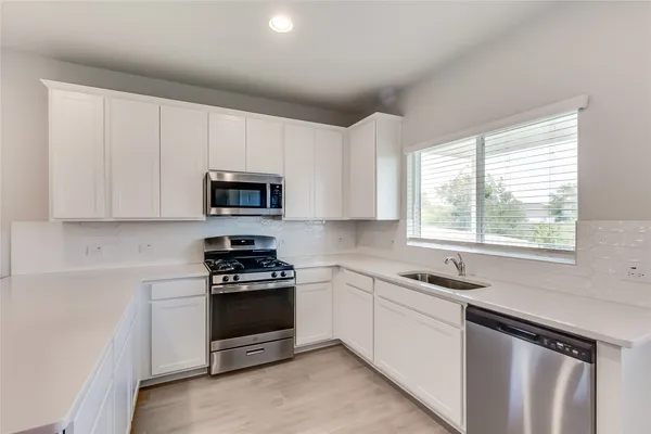 a kitchen with white cabinets and appliances