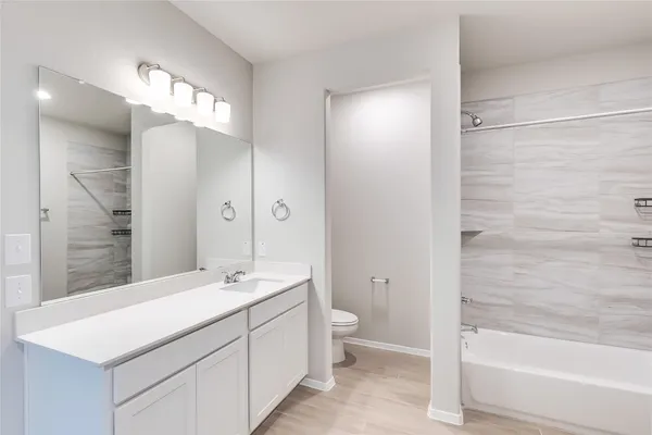 a bathroom with a double vanity sink a toilet and shower