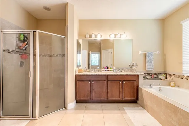 a spacious bathroom with a double vanity sink a mirror and a bathtub